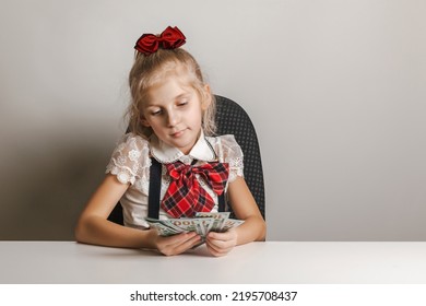 Little Girl In School Uniform Holds A Fan Of Hundred Dollar Bills. Teaching Children Financial Literacy.