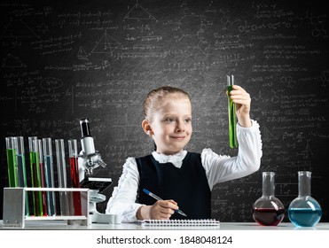 Little girl scientist examining test tube with chemical reagent. Research and education in school. Chemical laboratory with microscope and glass flasks. Schoolgirl making experiment in chemistry class - Powered by Shutterstock