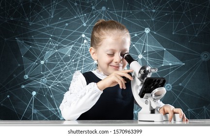 Little girl scientist looking through microscope in classroom at biology lesson. Research and discovery. Formal education in modern school. Schoolgirl in schoolwear making experiment in class. - Powered by Shutterstock