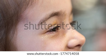 A little girl with sequins on her face close-up.