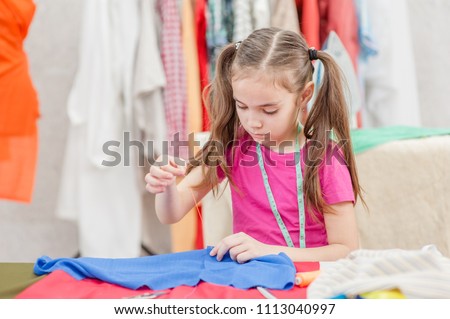 little girl sewing with a needle and thread. Hobby sewing concept