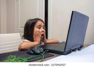 Little girl is shocked by what she sees on the computer screen - Shutterstock ID 2175942927