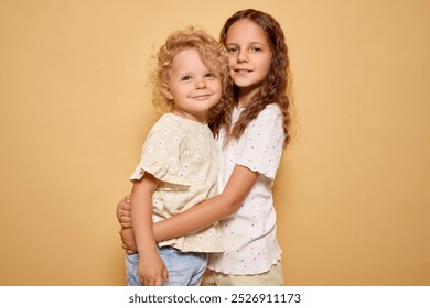 Little girl showing her affection for her baby sister with warm embrace reflecting strong sibling bond and happiness of childhood isolated over beige background - Powered by Shutterstock