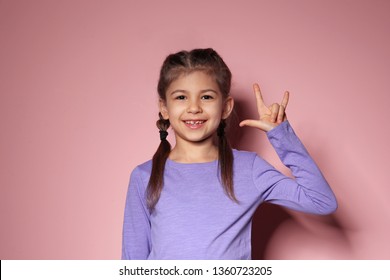 Little Girl Showing I LOVE YOU Gesture In Sign Language On Color Background