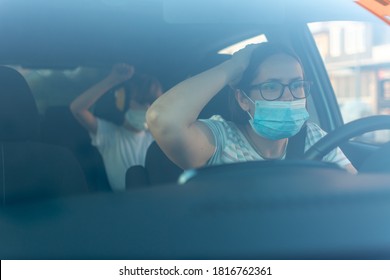 Little Girl Showing Stop Gesture To Angry Mother While Driving Car With Protective Mask Against Coronavirus. Angry Mother With Mask Driving Car And Daughter.