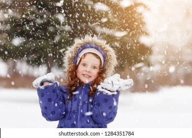 Little girl showing white teeth and stretches her hand to catch falling snowflakes. Happy childhood, medical, healthy lifestyle concept. - Shutterstock ID 1284351784