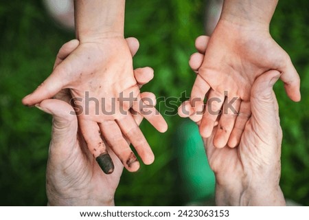 A little girl shows her filthy hands stained with black grease from playing outdoors which will be difficult to wash off