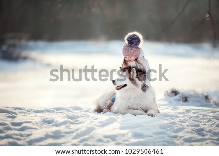 little girl with Siberian husky are walking in the winter forest