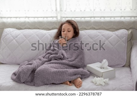 Little girl sick, child allergy, covered with blanket and drinking water