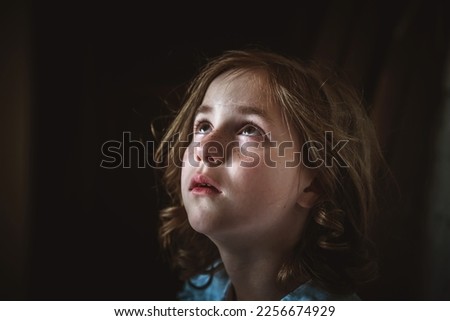 a little girl sits alone in a dark hallway. fear, loneliness