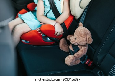 Little girl sitting in a car on a safety child car seat with her teddy bear. - Powered by Shutterstock