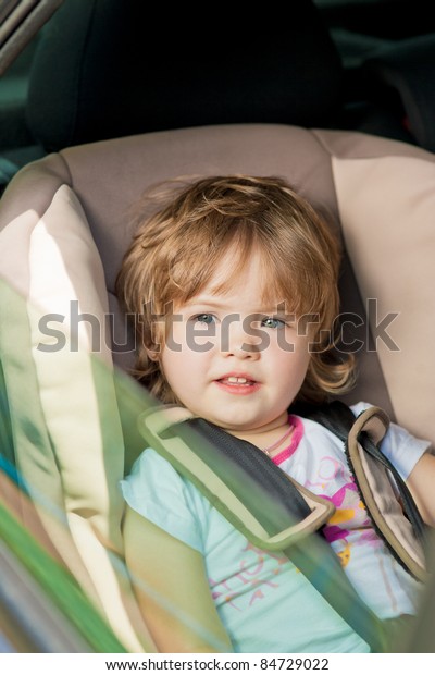 little girl sitting in car safety seat.shot made
through window pane
