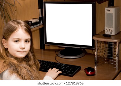 Little Girl Sitting At A Desk In A Home Office Using A Desktop Computer With A Large Blank White Screen Looking Back Over Her Shoulder At The Camera