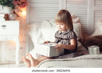 Little girl sitting on the bed with present box