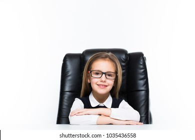 Little girl sitting on the desk at her workplace dressed as a businesswoman