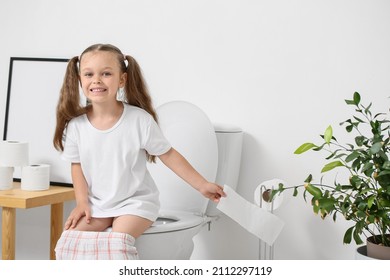 Little Girl Sitting On Toilet Bowl In Bathroom