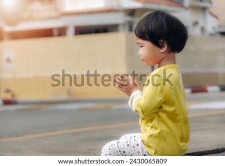 Little girl sitting praying who make merit worship a monk on the sidewalk of the road  
