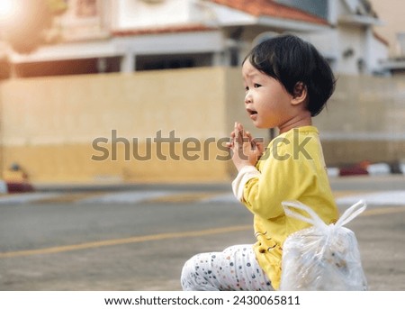 Little girl sitting praying who make merit worship a monk on the sidewalk of the road  