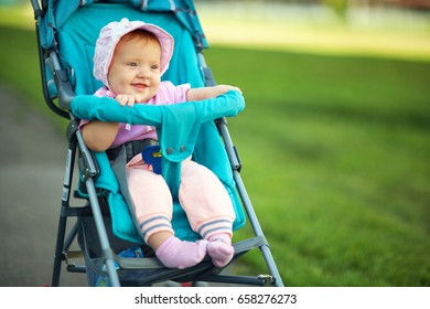 Little Girl Sitting In A Stroller. Baby For A Walk In A Pram. Child In Summer Outdoors