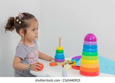 Little girl sitting at a table with toys, crayons and drawing sheets, with copy space - Powered by Shutterstock