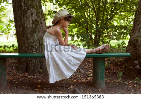 Little girl sitting in thought on a park bench