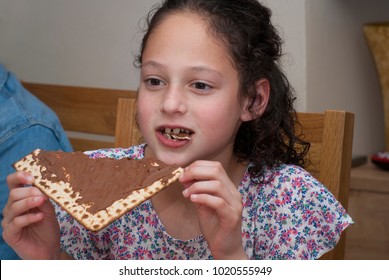 Little Girl Sitting For A Traditional Passover Seder Dinner And Eating Matzah With  Chocolate  Spread - Tasty Snack For Pesach Jewish Holiday That Kids Love.