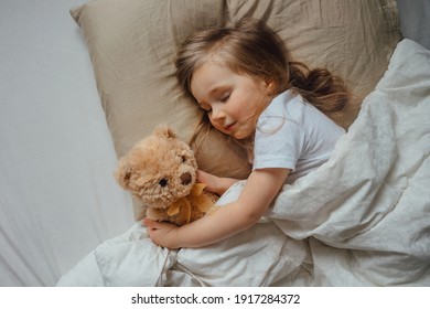 Little girl sleeping in bed embracing soft toy at home, top view - Powered by Shutterstock