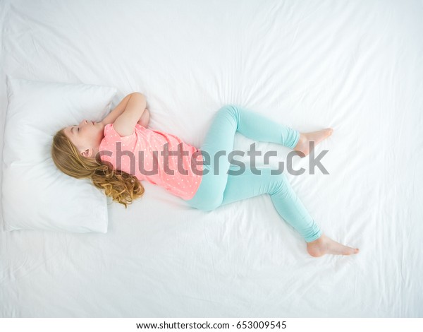 The little girl sleeping on the bed. view from above. view from above