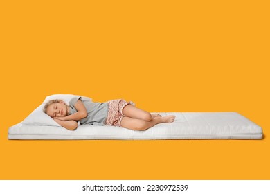 Little girl sleeping on comfortable mattress against orange background, space for text - Powered by Shutterstock