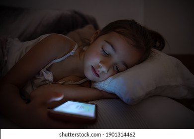 Little girl sleeps with the included smartphone in her hand. The concept of addiction to cartoons and games. - Shutterstock ID 1901314462