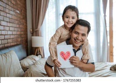 little girl smiled hugging her father from behind while holding a paper symbol of the heart which means to love each other - Shutterstock ID 1767255383