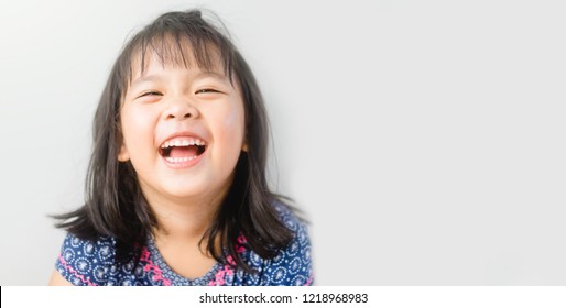 Little Girl Smiling And Laughing In The Camera On White Background.Little Asian Girl Smiling With Perfect Smile And White Teeth.4 Years Old Girl Child Showing Front Teeth With Big Smile.