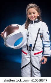 Little girl in space suit holding helmet  and smiling at camera 