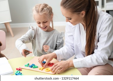 Little girl with speech therapist composing words of letters in office