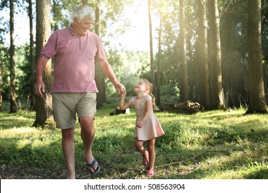 Little girl spending time with grandfather in the park.