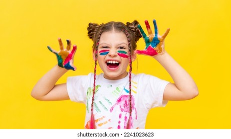 A little girl stained in multicolored paints, portrays a growling beast. The art of painting with paints for children. School creative courses for teenagers. - Shutterstock ID 2241023623