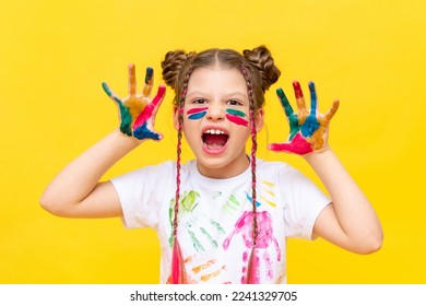 A little girl stained in multicolored paints, portrays a growling beast. The art of painting with paints for children. School creative courses for teenagers. - Shutterstock ID 2241329705