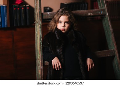 Little girl stand by the ladder in the library. Books - Shutterstock ID 1293640537