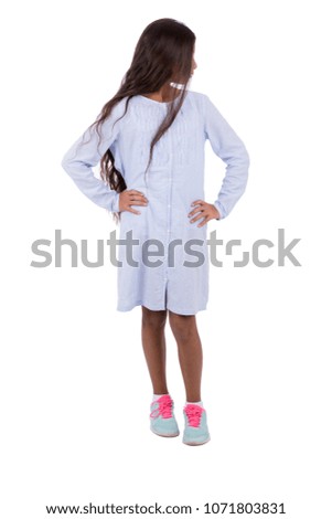 Little girl standing hands on waist, looking beside, isolated on a white background.