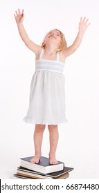  Little Girl Standing On A Pile Of Books Reaching Up With Her Hands