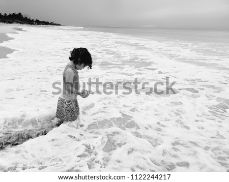 Little girl standing in the sea with sand in her hand in Varadero Cuba at the year 2018