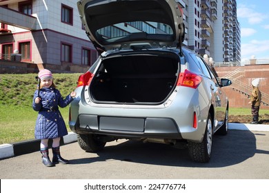 Little Girl Standing With Socket Wrench And Boy Near Open Trunk Of Car