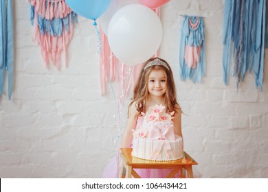 A little girl stands near a cake with balloons / little girl celebrates the day her birthday