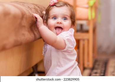 little girl stands near the sofa at home - Powered by Shutterstock