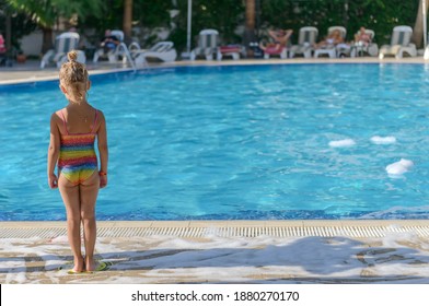 Little girl stands near the in tropical blue swimming pool in summer. In Water In a Blue Pool. Turkey. Kemer. Mediterranean sea. November 3, 2020