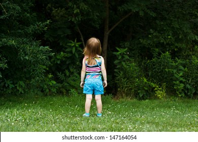 Little girl staring into woods