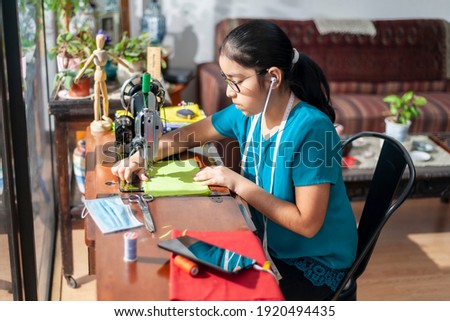Little girl staying at home during the coronavirus, learns to sew clothes online.