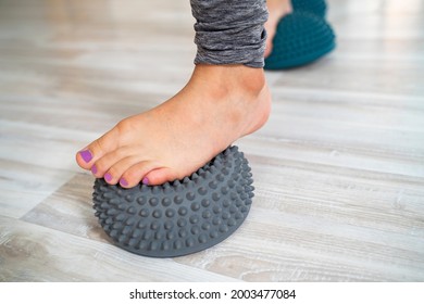 Little girl stepping on rubber hedgehog ball for flat feet correction 