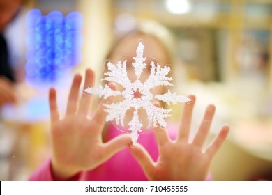 Little Girl Sticking Christmas Snowflake Sticker To A Window. Decorating Home For Christmas. Celebrating Xmas At Home.