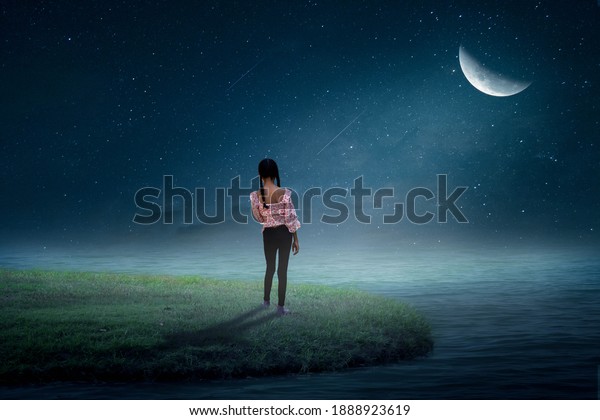 The little girl stood looking at the moon on a grassy island by the sea in a lonely beach. Bedroom wallpaper mural design. 